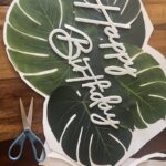 4.  CUT AROUND THE PALM LEAVES: Carefully cut around the entire glued sign making sure to leave a border around it. I also like to cut into the curves of the leaves to make it more detailed and realistic.